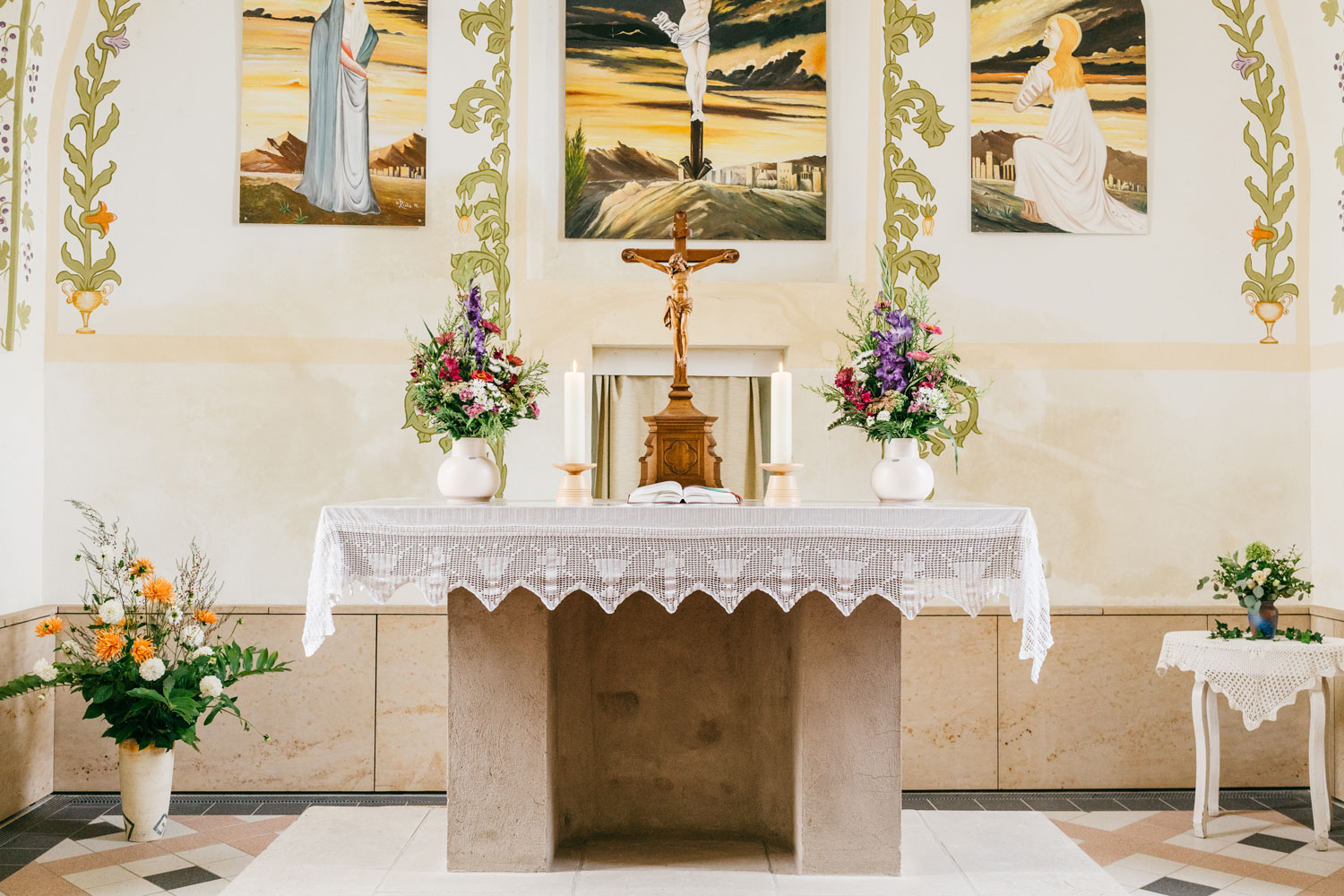 Altarrraum der Kirche St. Moritz mit Kreuz und Blumensträußen.