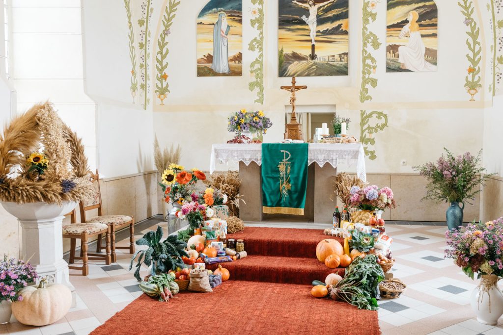 Geschmückter Altarraum einer Kirche zum Erntedankfest mit Blumensträußen und Erntegaben.