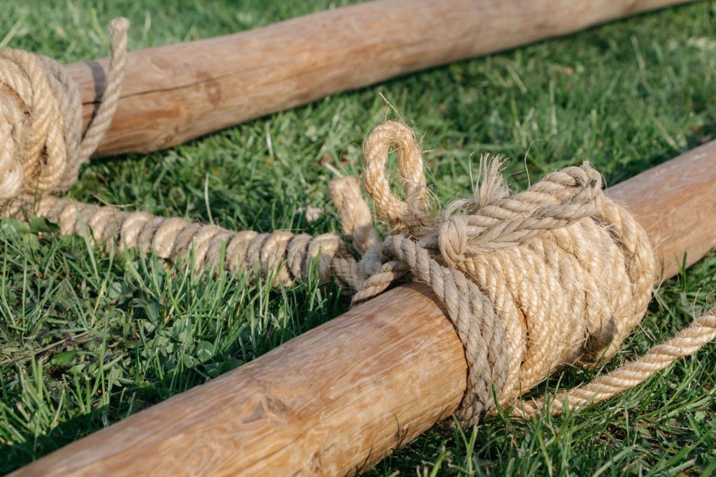 Strick um einen Holzpfahl geknotet, Holzpfahl liegt im Gras