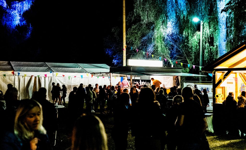 Menschen feiern bei Nacht auf der Löhmaer Festwiese, Festzelte im Hintergrund.