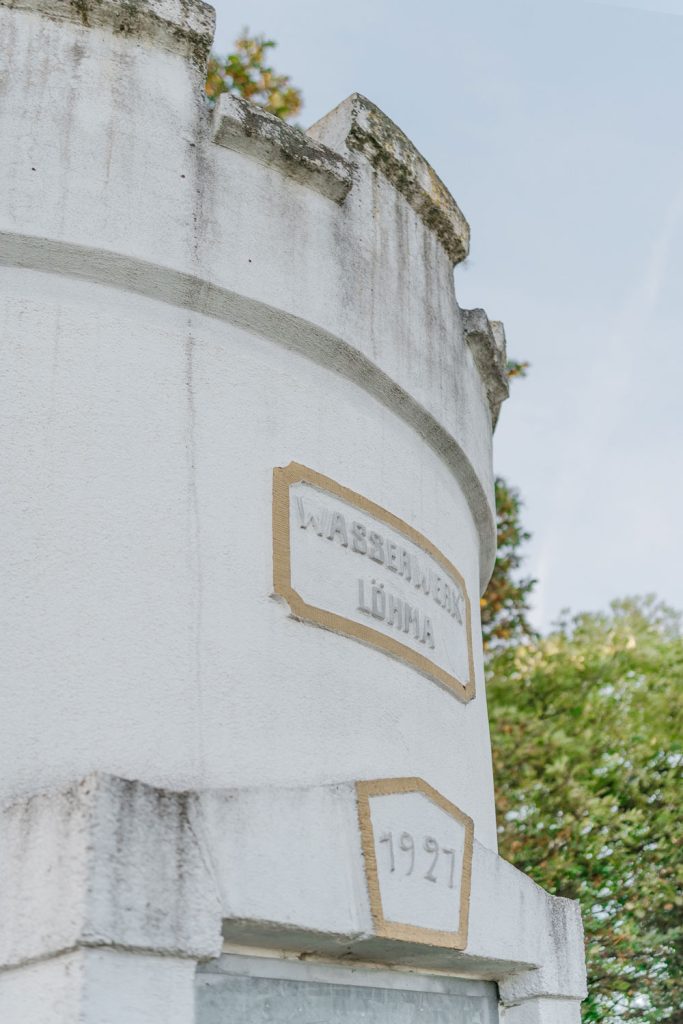 Weißer Steinturm mit goldener Inschrift: Wasserturm Löhma, 1927