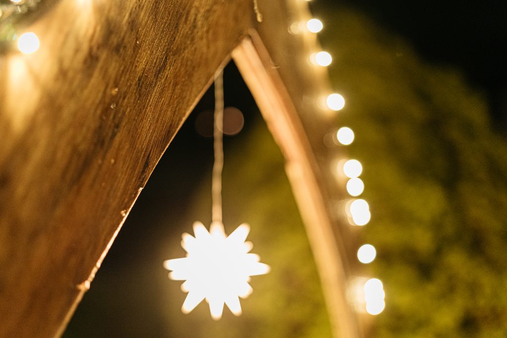 Das Holz des Spitzbogens erscheint im Vordergrund. Im Hintergrund leuchtet ein Stern.