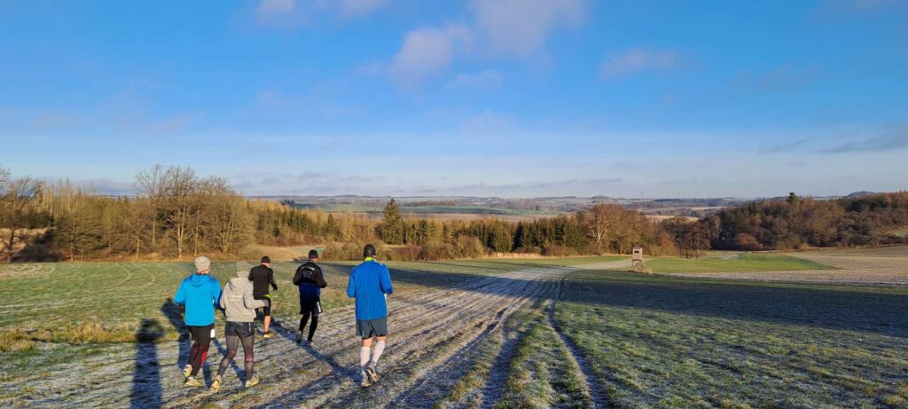 Die Läufer des Silvesterlaufes joggen auf einem Feld.