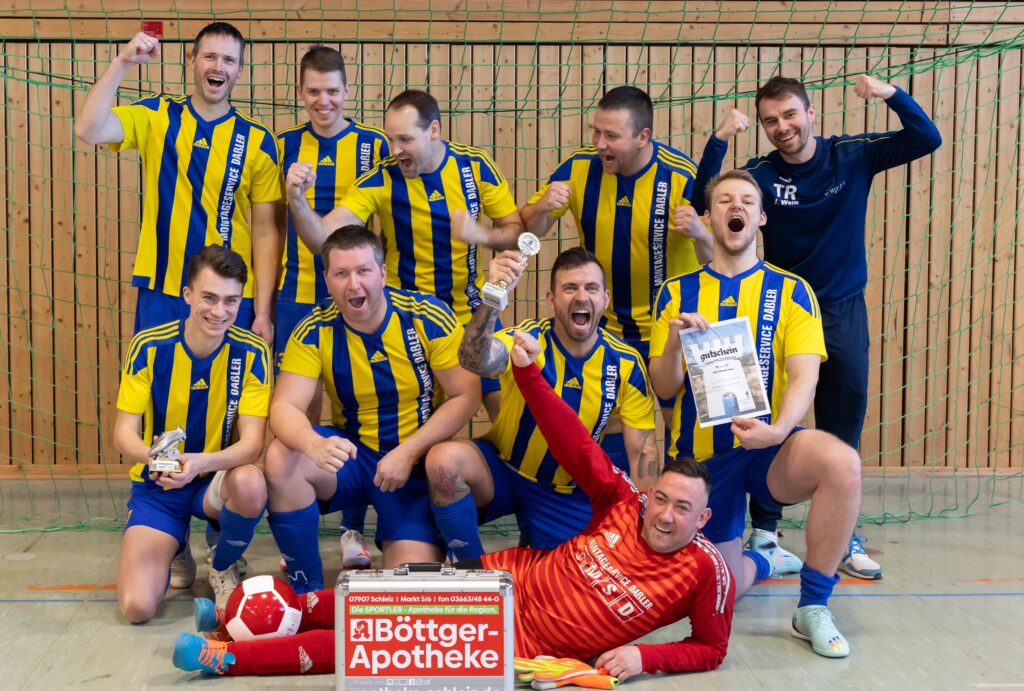 Zehn jubelnde Spieler des SV Löhma in gelb-blauen Trikots.