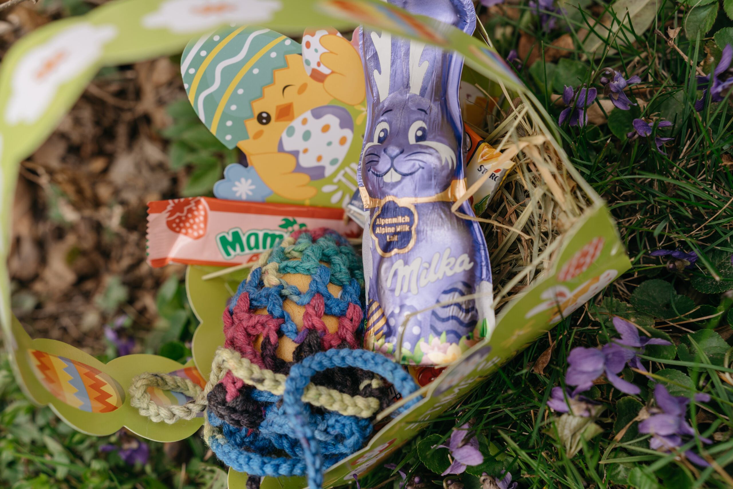 Osterkörbchen mit Süßigkeiten und einem gehäkelten Eiernetz